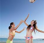 Two young women playing volleyball on beach