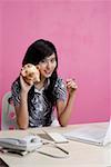 Young woman sitting by table and holding piggy bank, smiling, portrait