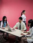 Businessman using laptop while businesswomen sitting beside her