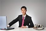 Young businessman sitting at desk with laptop and telephone