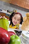 Girl in kitchen holding fruit and smiling