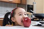 Portrait d'une jeune fille eating apple dans la cuisine