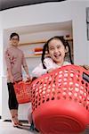 daughter carrying basket and smiling while mother standing in background with basket
