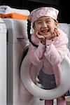 Portrait d'une jeune fille se penchant sur la machine à laver