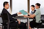 Businesswoman passing file to businessman, smiling