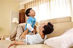 Father playing with son in sofa