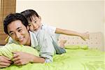 Son riding on father on bed