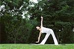 Young woman practising yoga on lawn