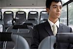 Businessman sitting in bus, smiling