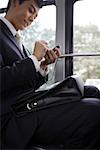 Businessman using mobile phone in bus