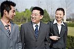 Business people standing in park, smiling