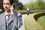 Young businessman using mobile phone, close-up, smiling