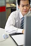 Young businessman sitting in an office talking on the telephone