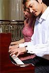 Young man and young woman playing piano