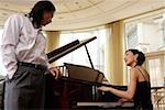 Junger Mann mit einer jungen Frau, die Klavier spielen