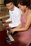 Young lovers playing piano in hall