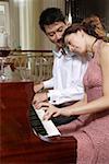 Young lovers playing piano in hall intimately