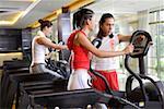 Young man instructing young woman on exercise machine