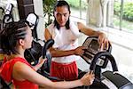 Young man instructing young woman on exercise bike