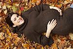 Femme enceinte se trouvant dans les feuilles d'automne