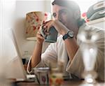 Portrait of Man Sitting in Front of Laptop Computer, Holding Mug