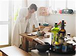 Man using Cell Phone and Laptop Computer in Kitchen