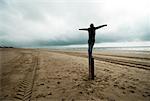 Jeune fille debout sur le Post sur la plage, Pays-Bas