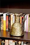 Close-up of an old pitcher in front of books in a shelf
