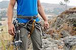 Mid section view of a male rock climber with climbing equipments around his waist