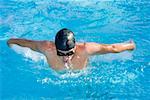 Young man swimming the butterfly stroke in a swimming pool