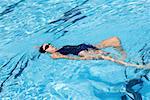 Vue grand angle d'une jeune femme au dos de la natation dans une piscine