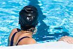 Profil de côté d'une jeune femme se penchant sur le rebord d'une piscine