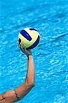 Close-up of a person's hand holding a water polo ball in a swimming pool