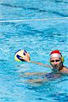 Mid adult man playing water polo in a swimming pool