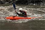 Profil de côté d'un jeune homme kayak dans une rivière