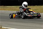 Person driving a go-cart on a motor racing track