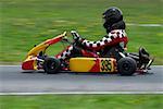Side profile of a person go- carting on a motor racing track