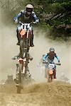 Motocross riders riding motorcycles on a dirt road