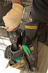 Mid section view of a man putting pliers into a tool belt