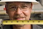 Close-up of a male construction worker holding a tape measure