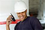 Close-up of a male construction worker talking on a walkie-talkie and smiling