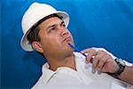 Close-up of a male construction worker holding a pen and thinking