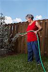 Side profile of a senior woman watering a plant