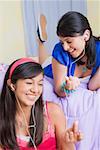 Teenage girl and a young woman listening to music with earbuds and smiling