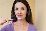 Portrait d'une femme adulte mid tenir une brosse à dents devant sa bouche