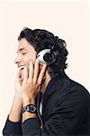 Close-up of a young man listening to music and smiling