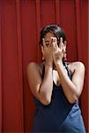 Portrait of a young woman covering her face with her hands