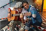 Young man playing a guitar and smiling with a young woman