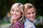 Portrait of two young women back to back and smiling