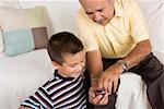 High angle view of a senior man showing a mobile phone to his grandson